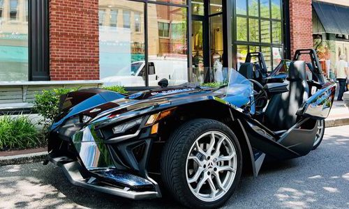 Black Polaris Slingshot three-wheel roadster rental parked on a downtown street