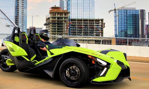 Lime green Polaris Slingshot R with manual transmission, driver wearing a full-face helmet